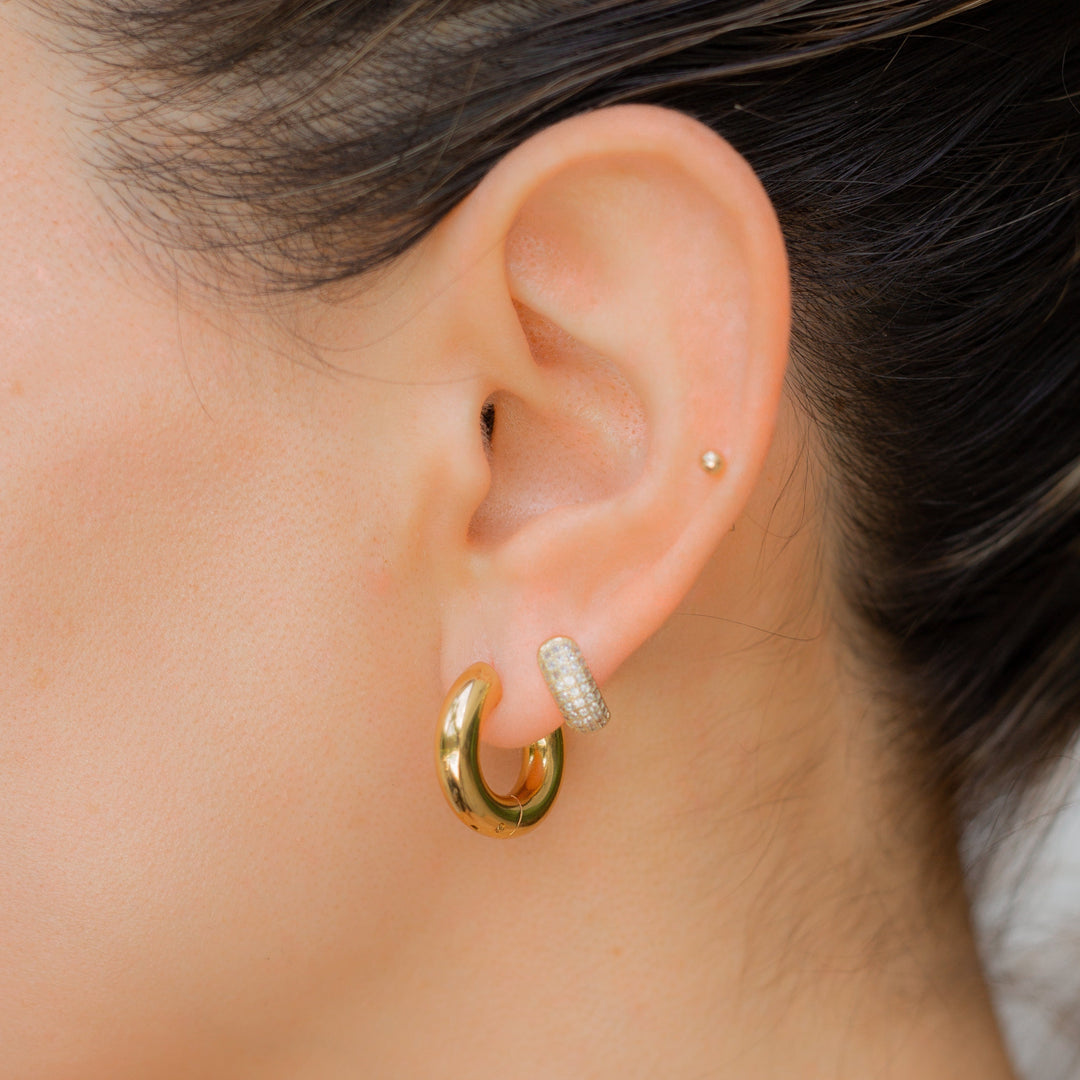 Ear wearing gold chunky huggie hoops