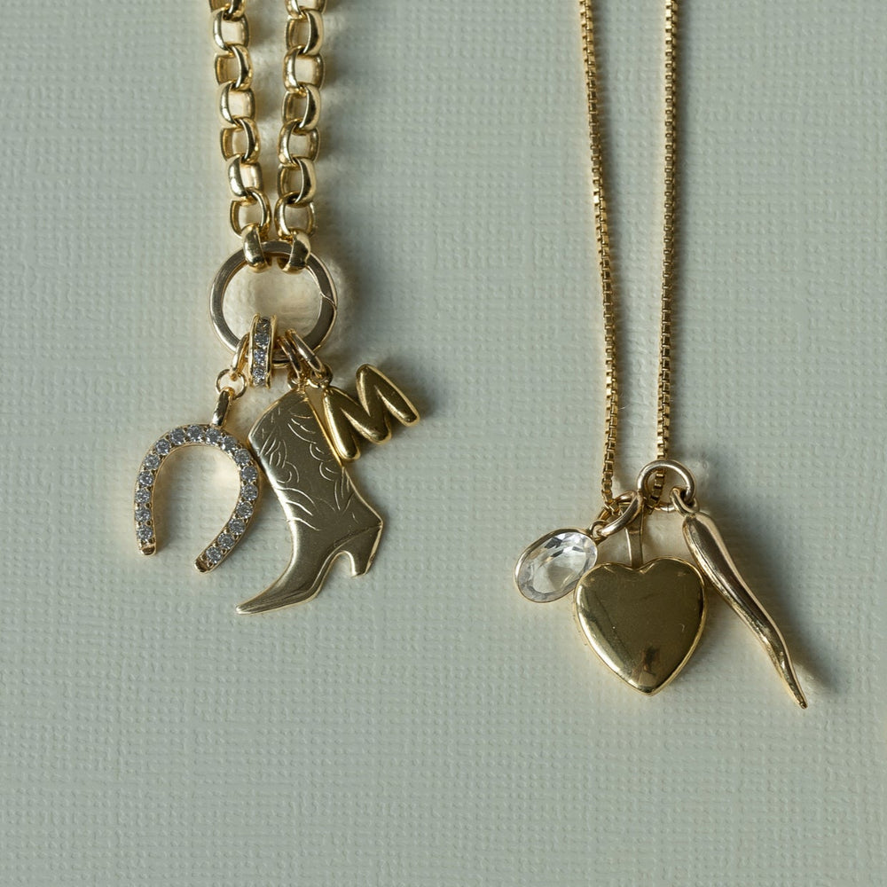 two gold necklaces with various charms on a light gray background