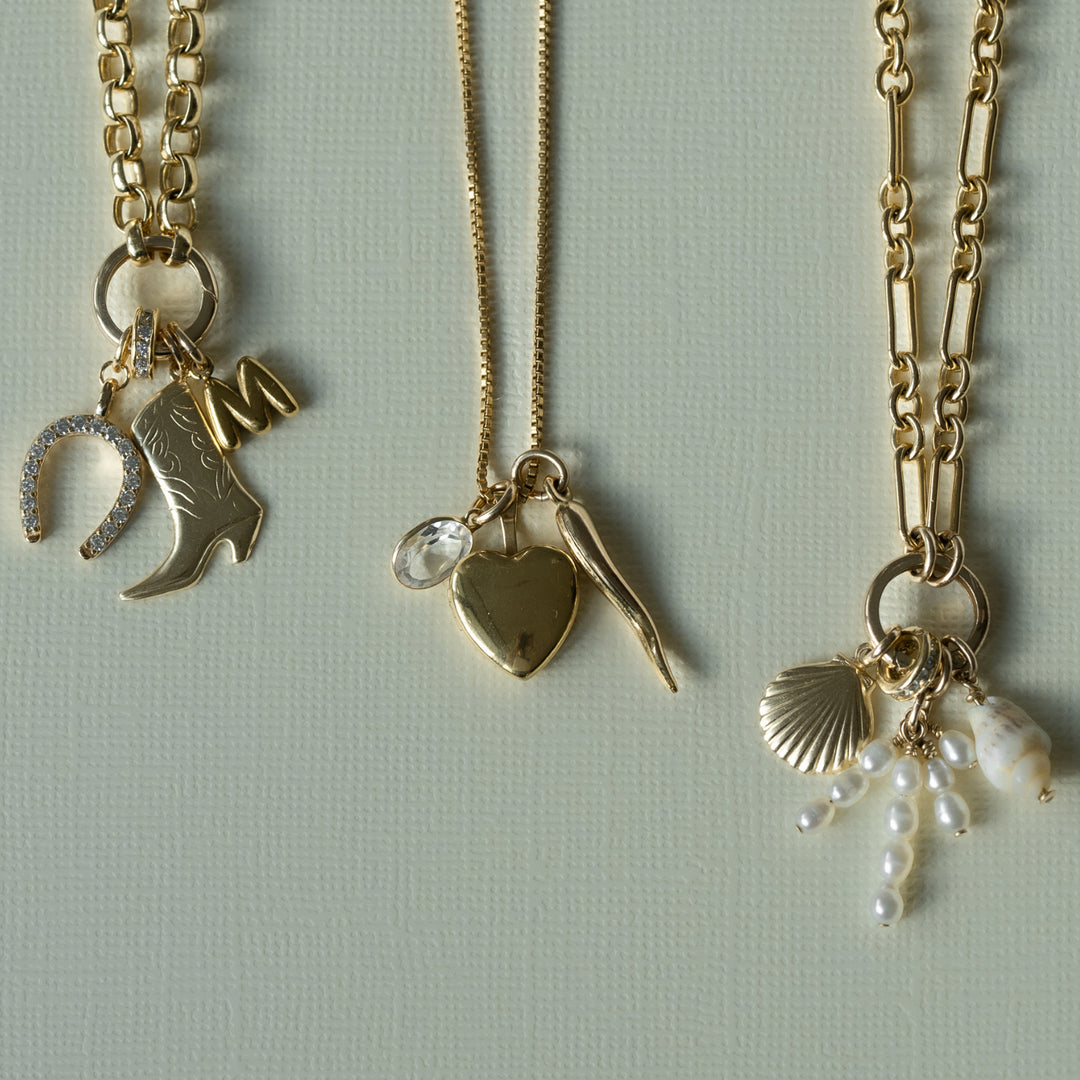 Gold necklaces with gold charms on a beige background 