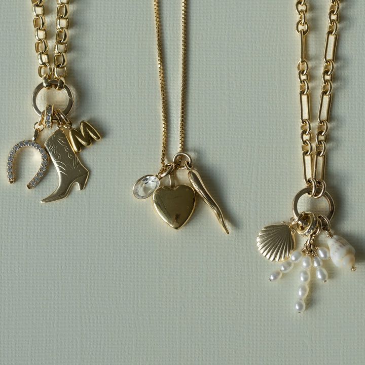 Gold necklaces with gold charms on a beige background 