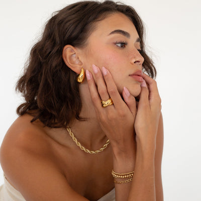 model wearing mixed metals cross over ring and dome drop earring 