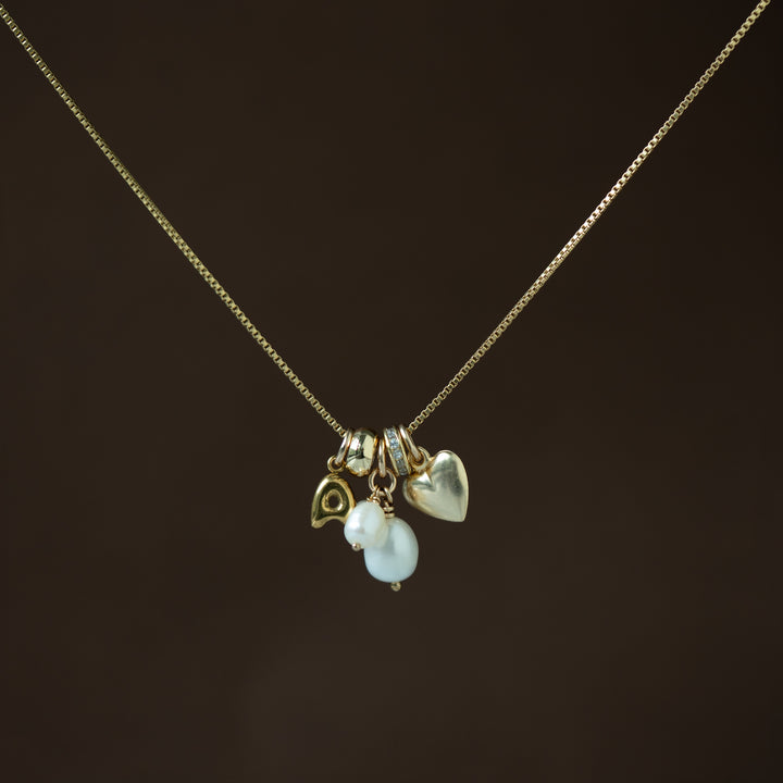 gold necklace with gold and pearl charms on a dark brown background