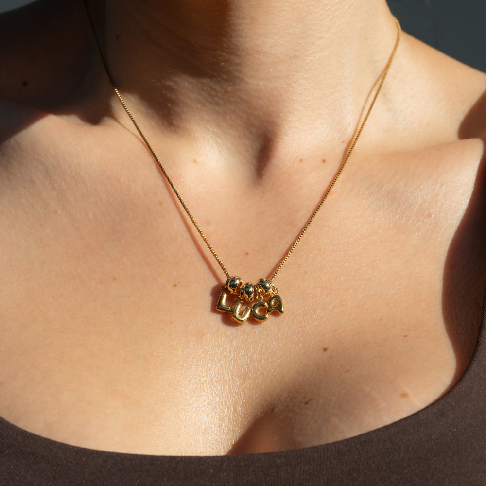 Gold necklace with small pendants on a person's neck