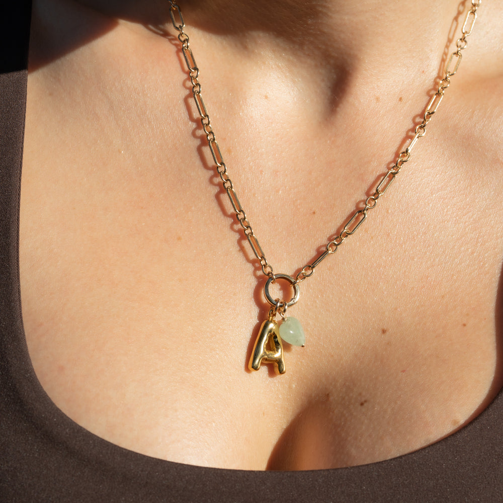 Gold necklace with a 'A' pendant on a person's neck