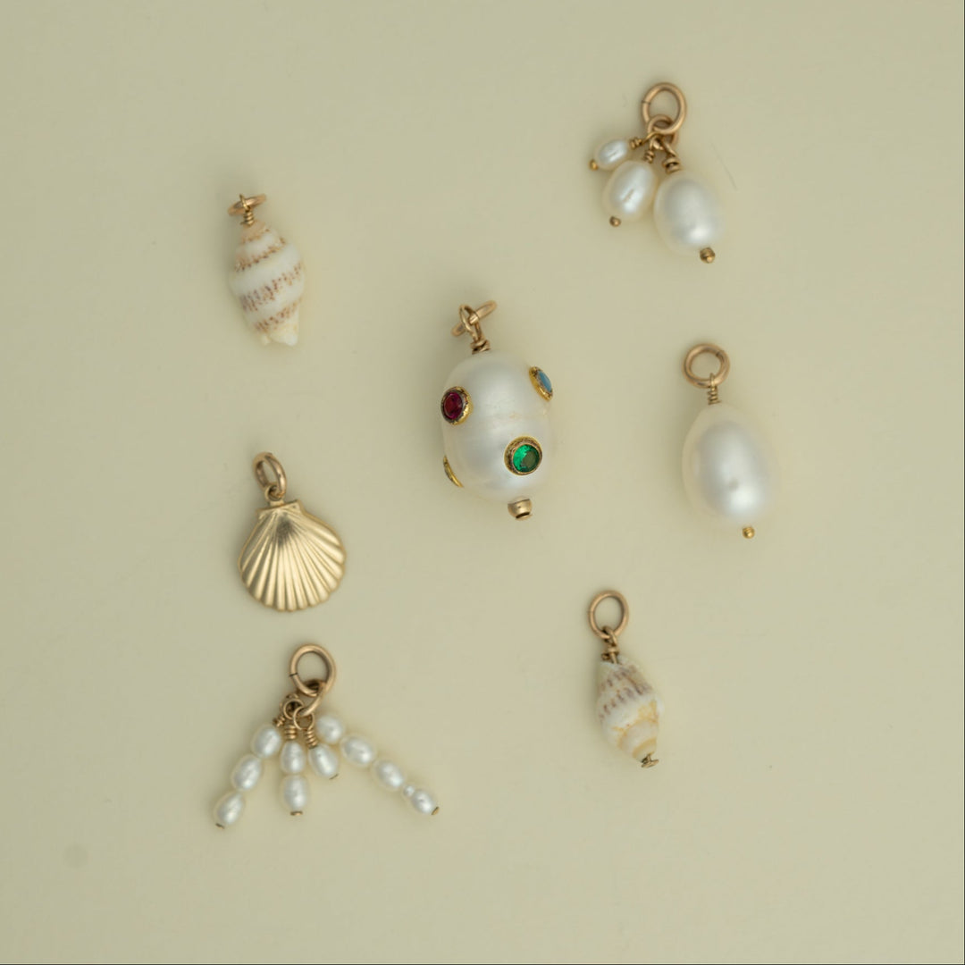 Collection of pearl and shell charms on a beige background