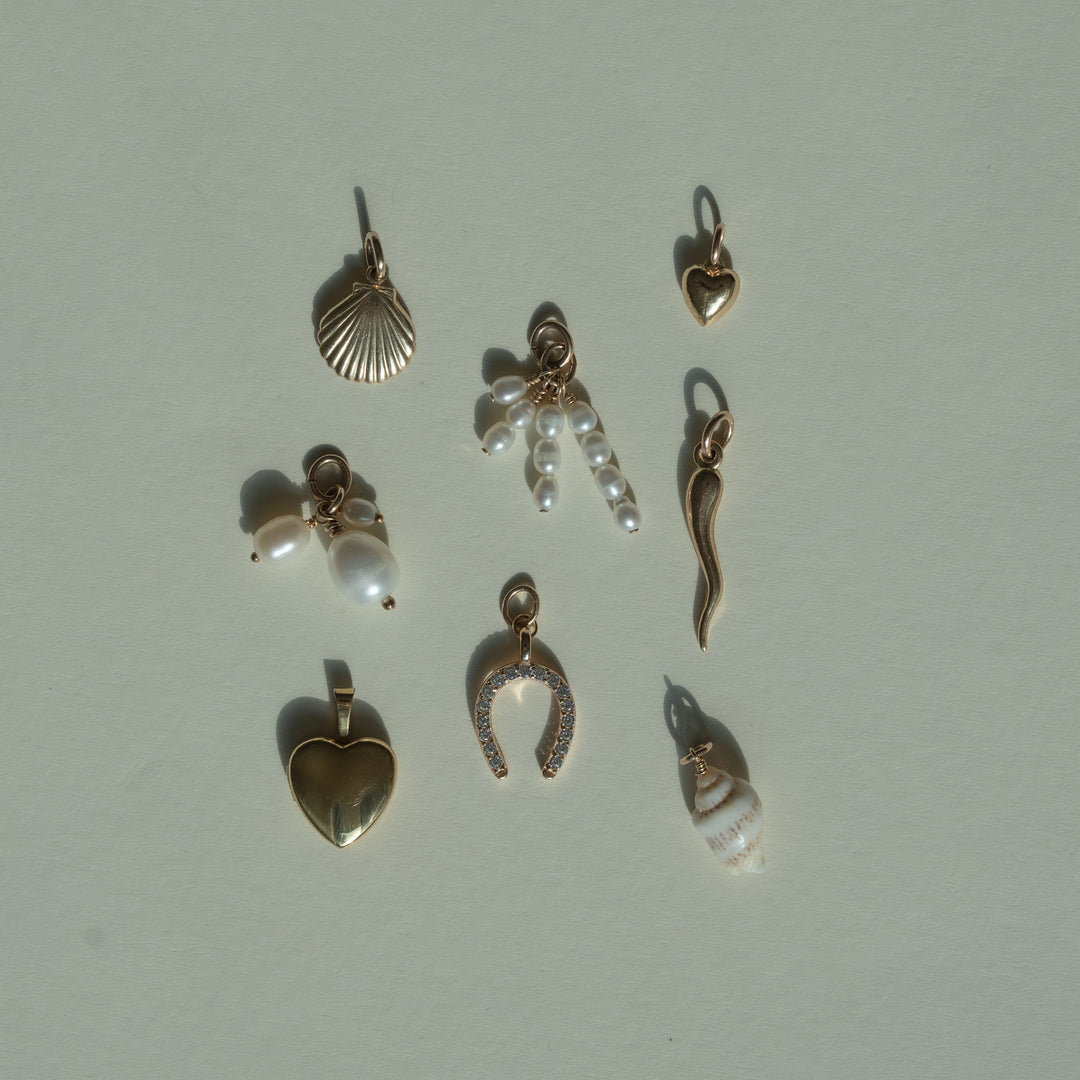 flat lay of gold and shell charms on a beige background