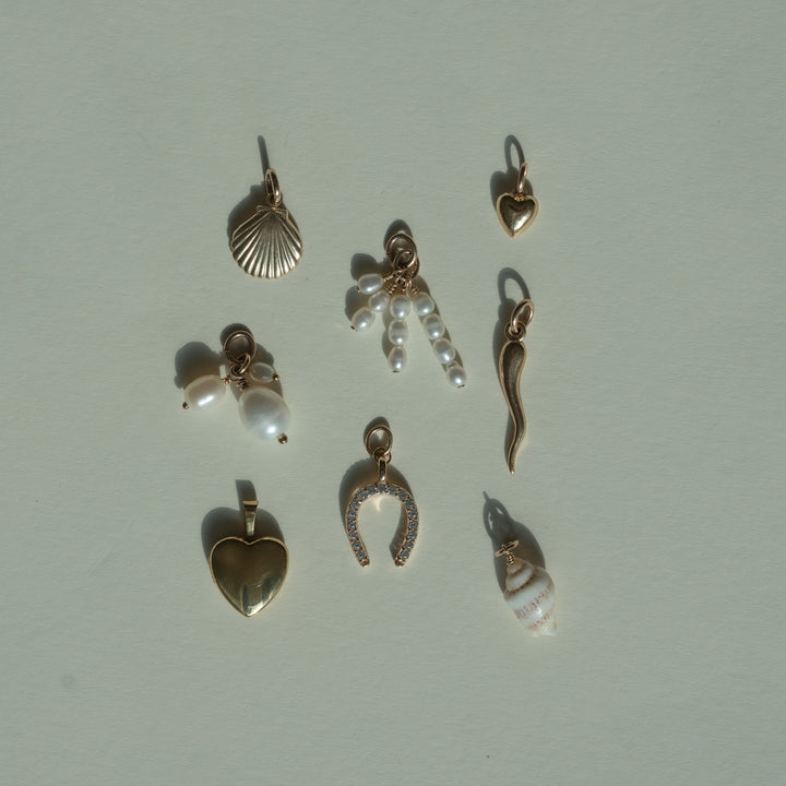flat lay of gold and shell charms on a beige background