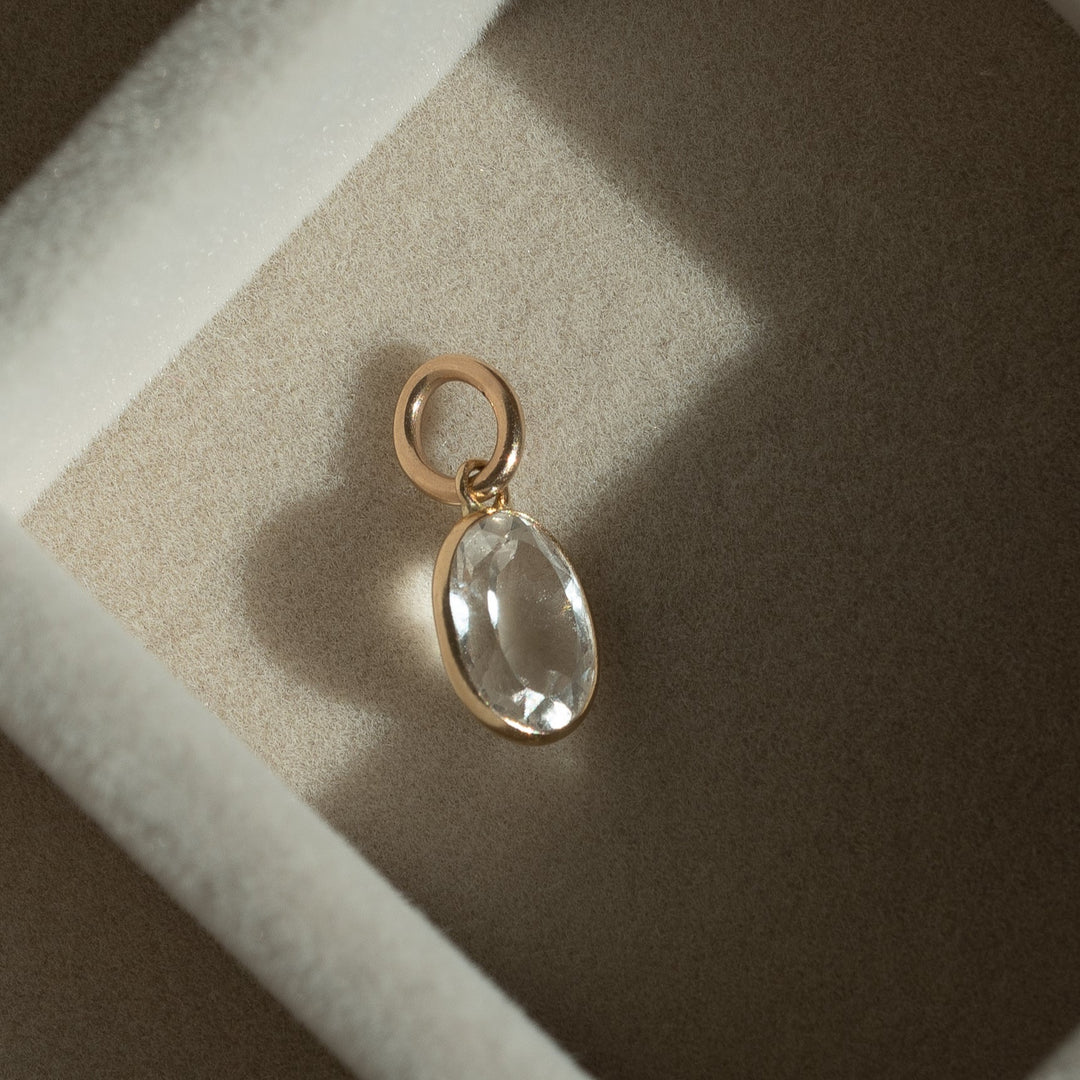 Gold pendant with a clear stone in a brown jewelry box