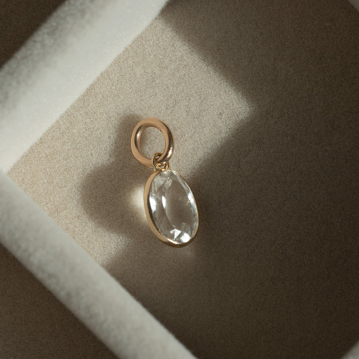 Gold pendant with a clear stone in a brown jewelry box