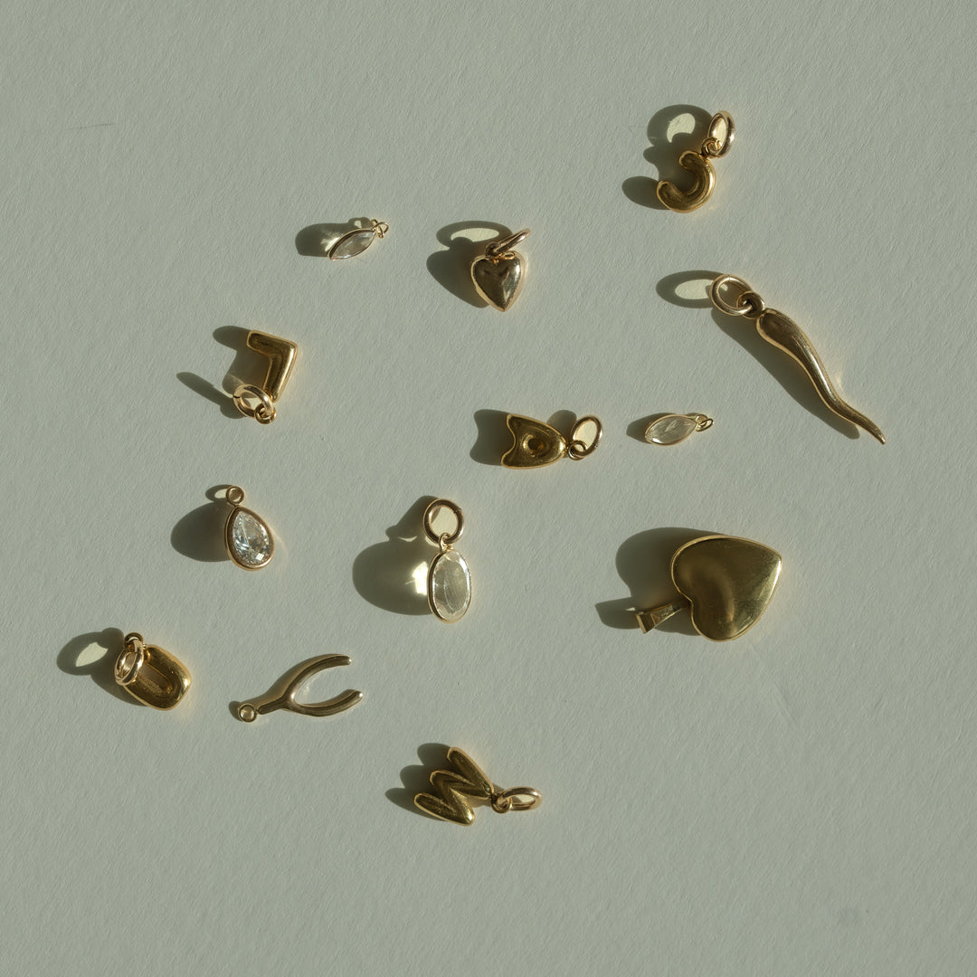 Collection of gold jewelry charms on a light beige background
