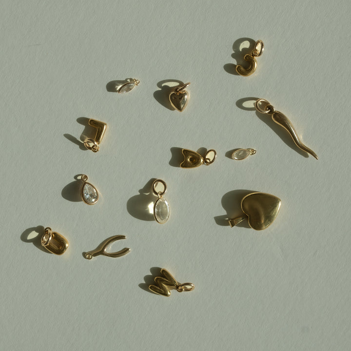 Collection of gold jewelry charms on a light beige background