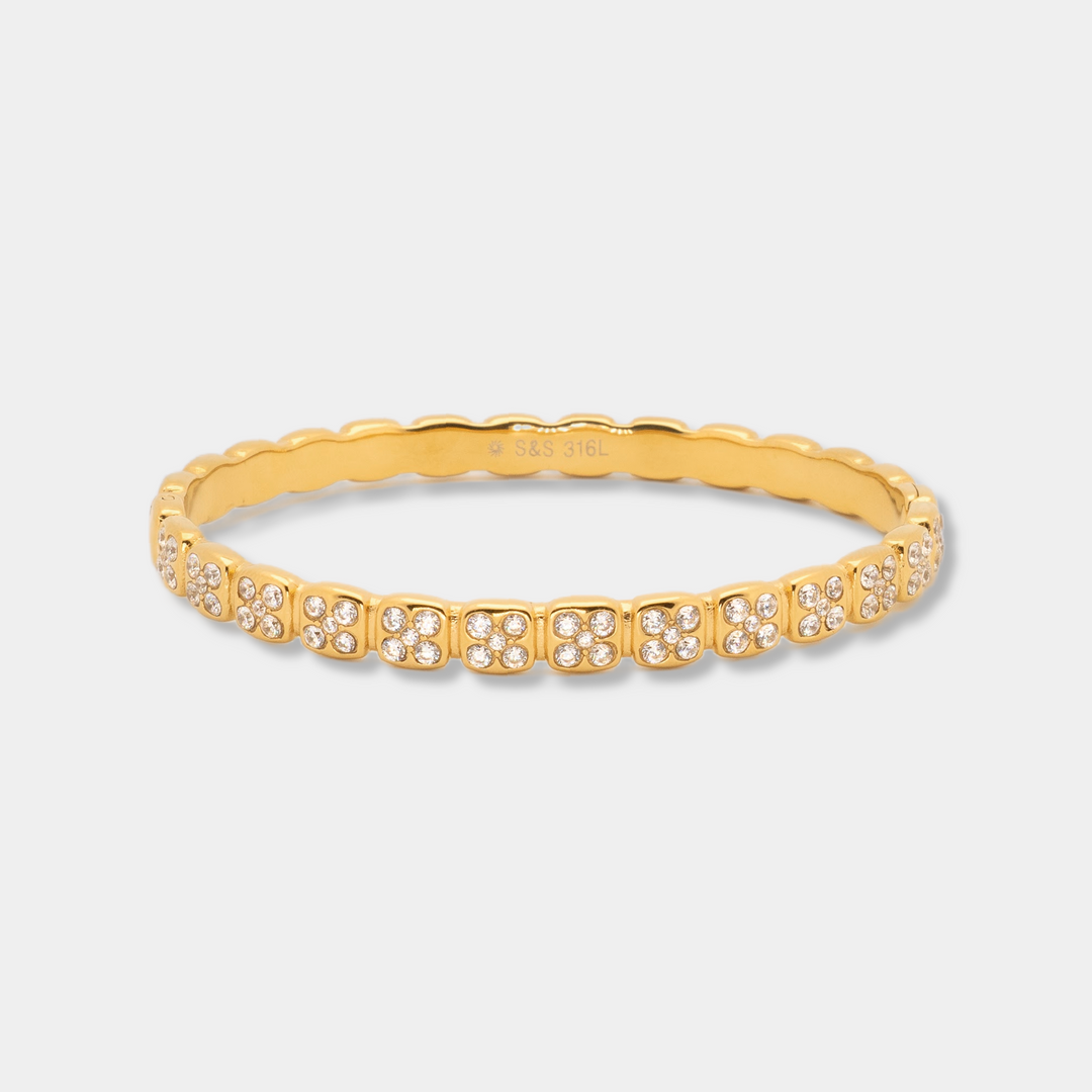 Gold bracelet with small diamonds on a light gray background