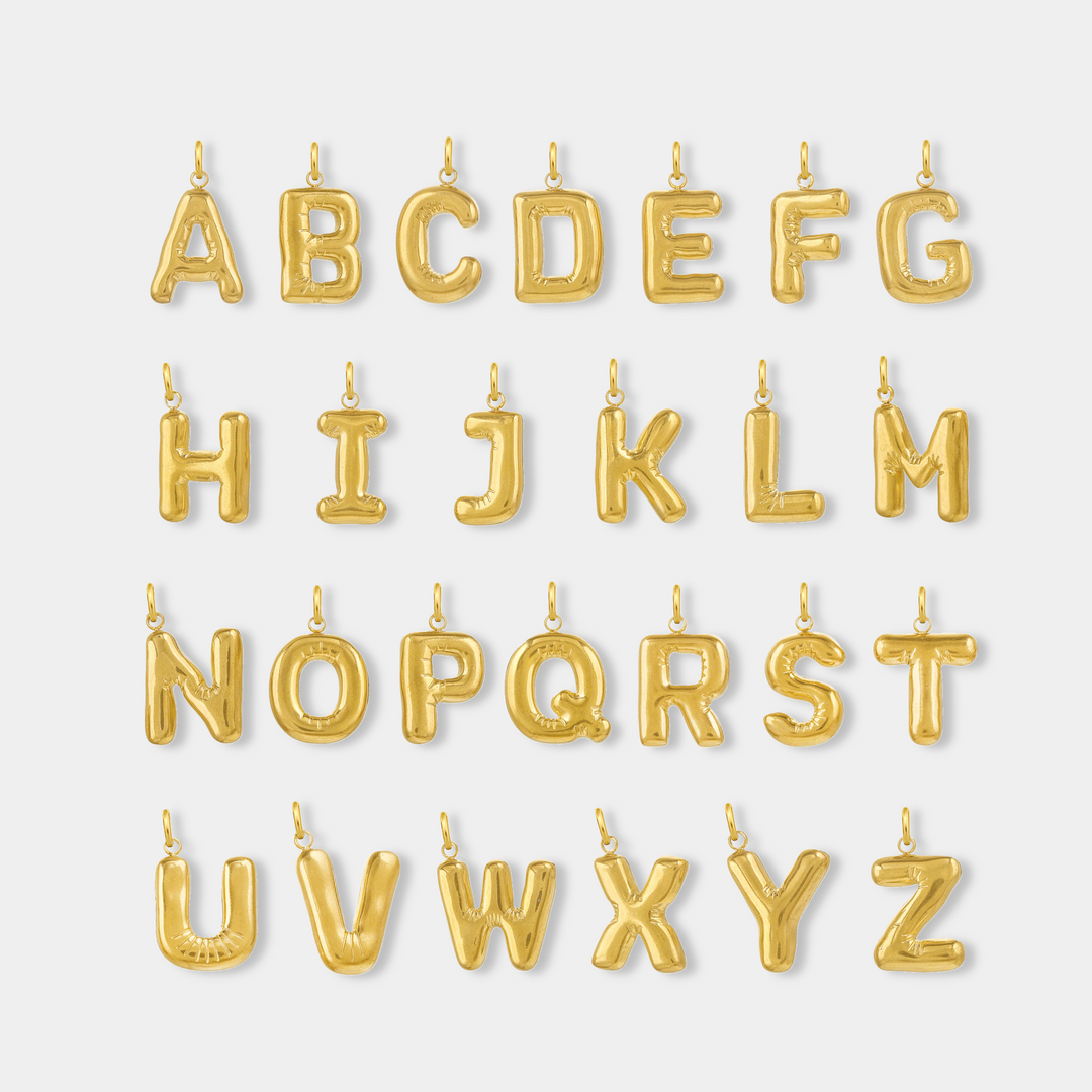 Gold letter charm pendants spelling out the alphabet from A through Z on a light gray background  #letter_a