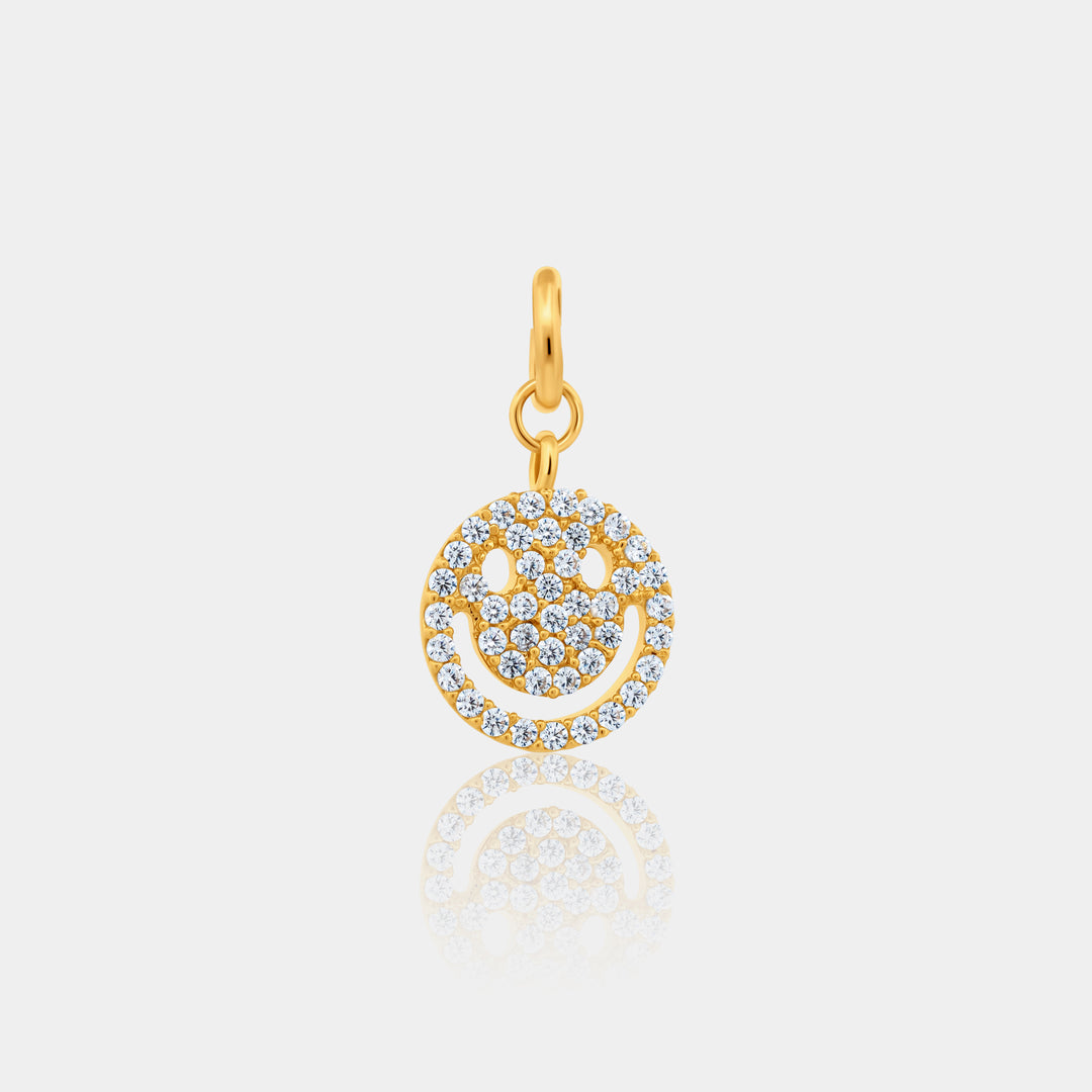 Gold smiley face pendant with clear stones on a light gray background