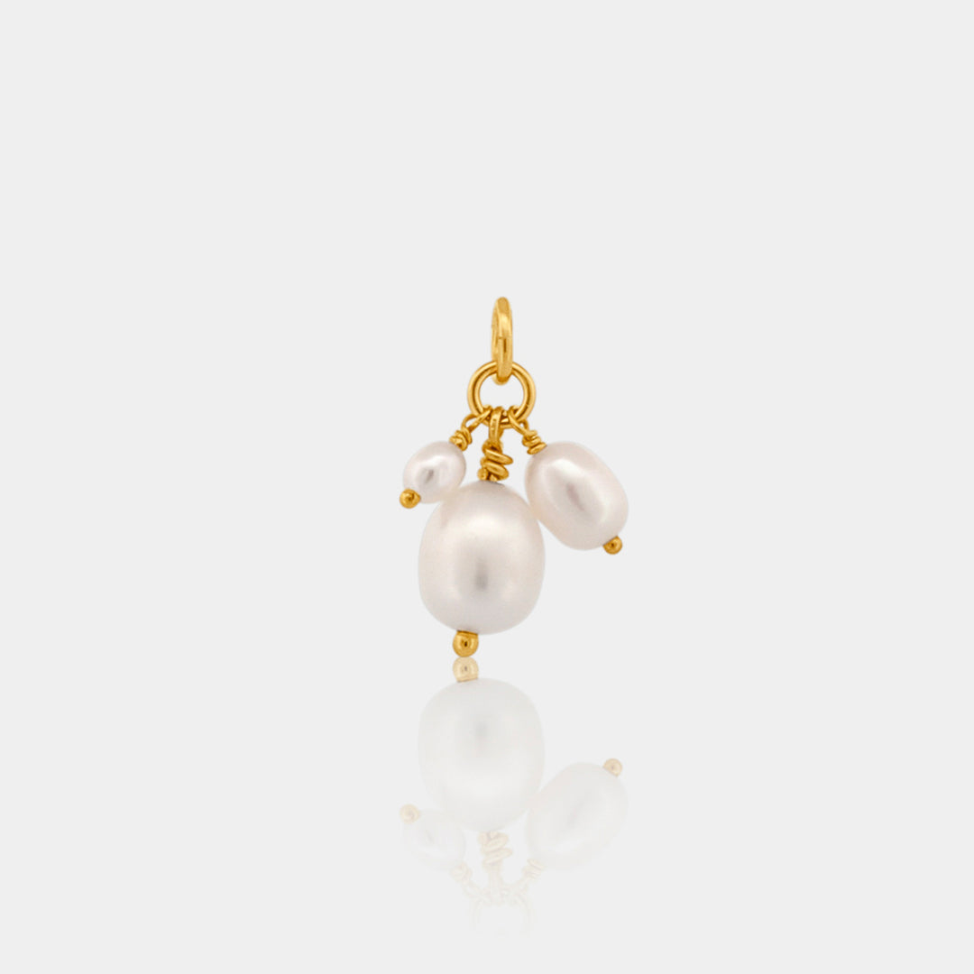 Gold pendant with white pearls on a light gray background