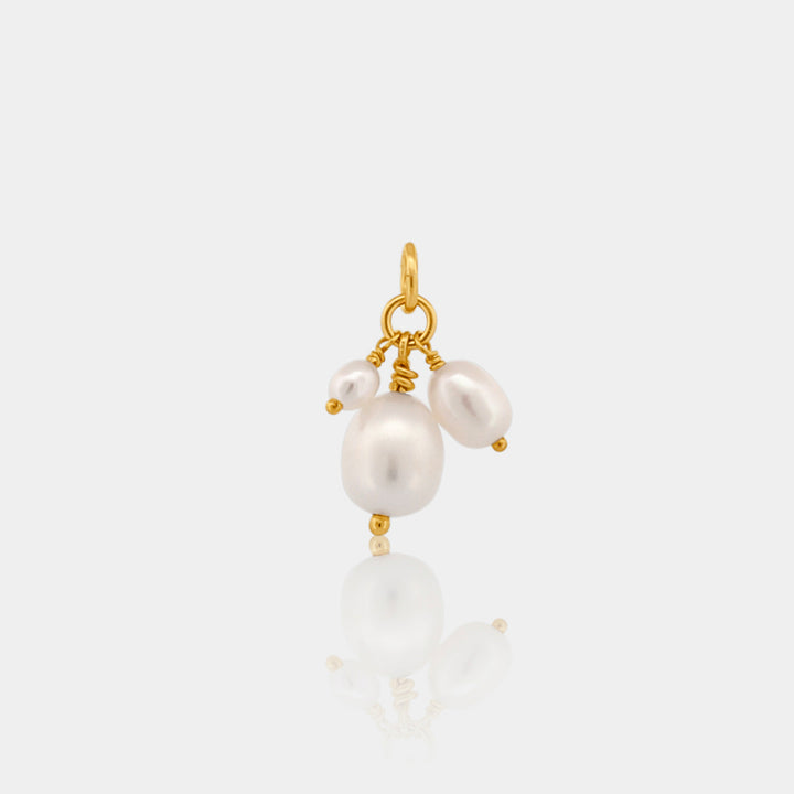 Gold pendant with white pearls on a light gray background