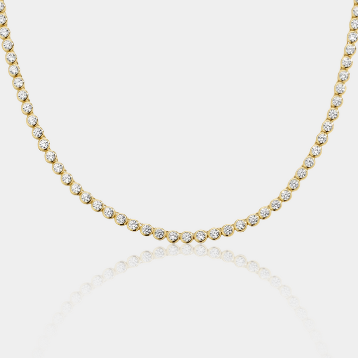 Gold necklace with clear stones on a light gray background