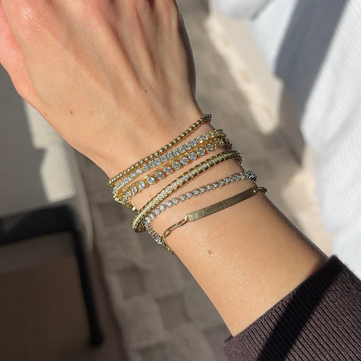 Hand wearing multiple bracelets with a blurred background