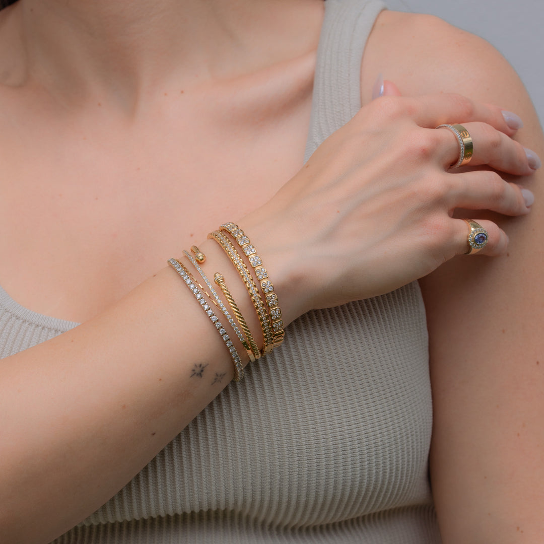 Close-up of a person's arm wearing multiple gold bracelets and rings.