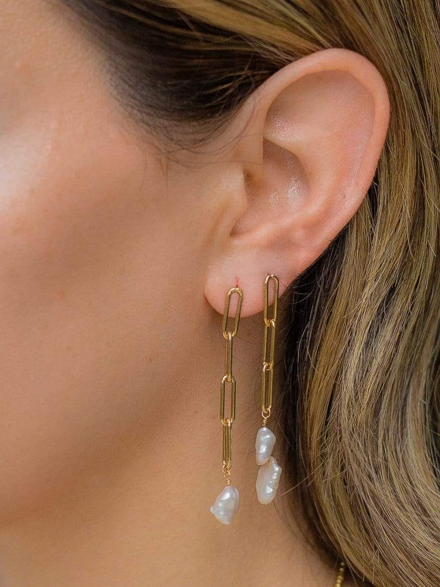 ear wearing gold paperclip earrings with pearl drops 