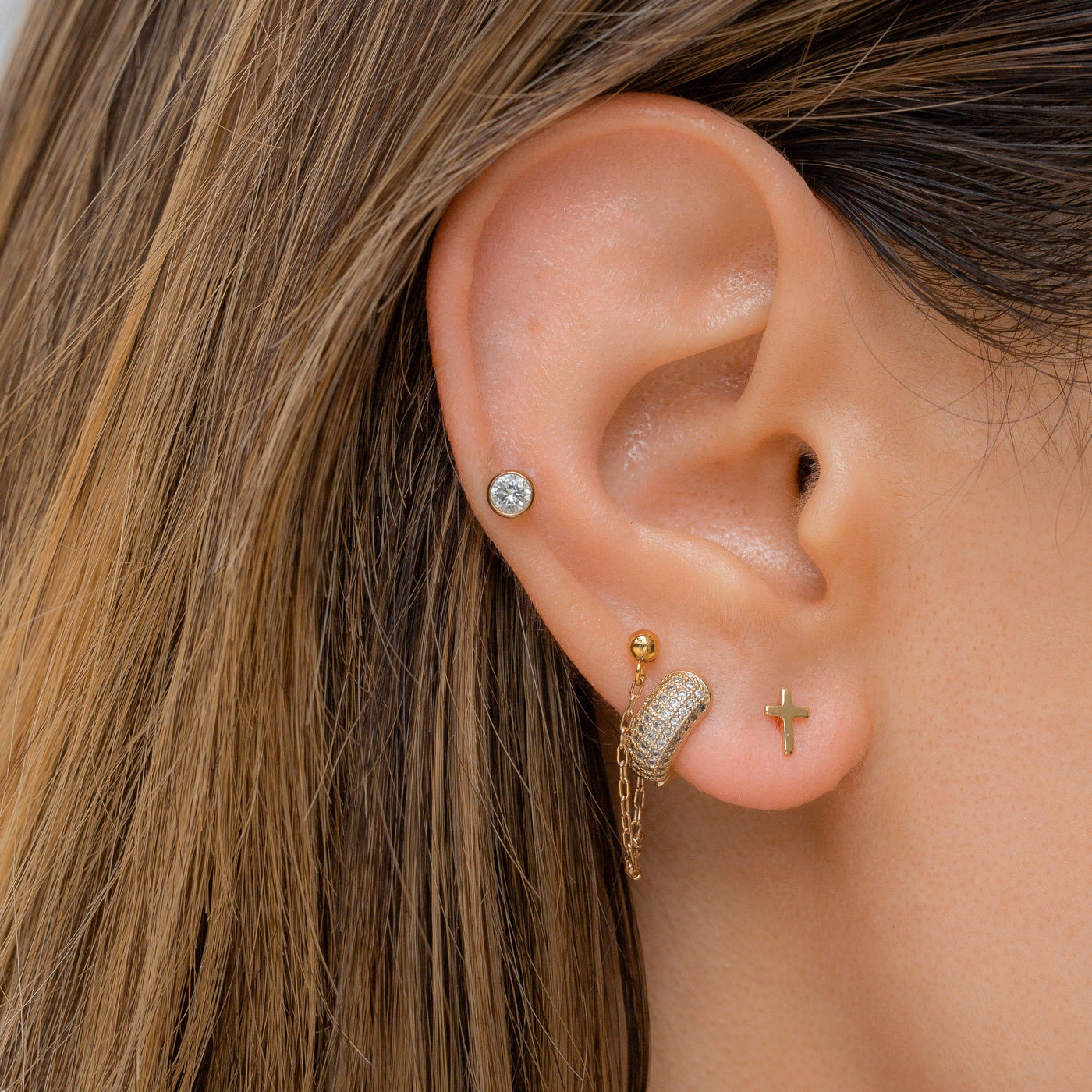 Ear wearing dainty cross stud earrings in 14k gold fill