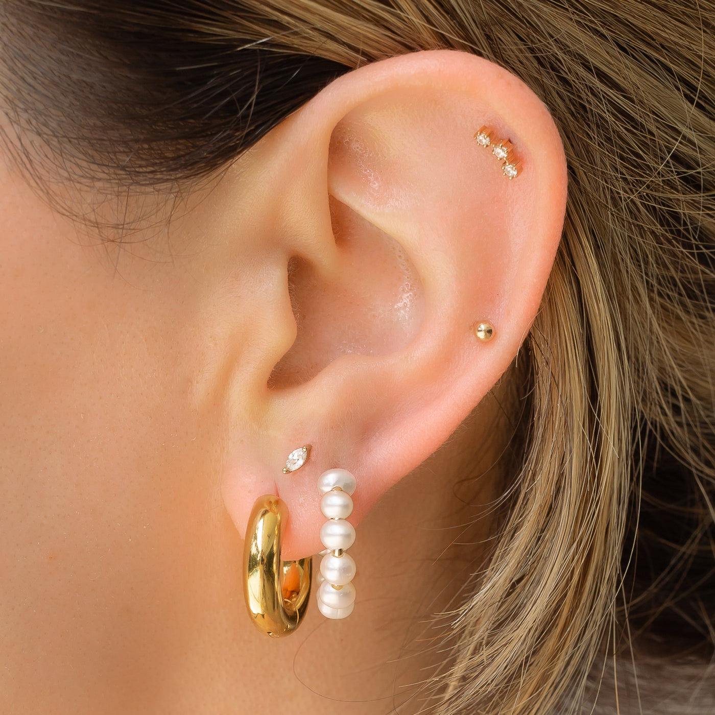 goldear wearing huggie earrings and pearl hoop earrings